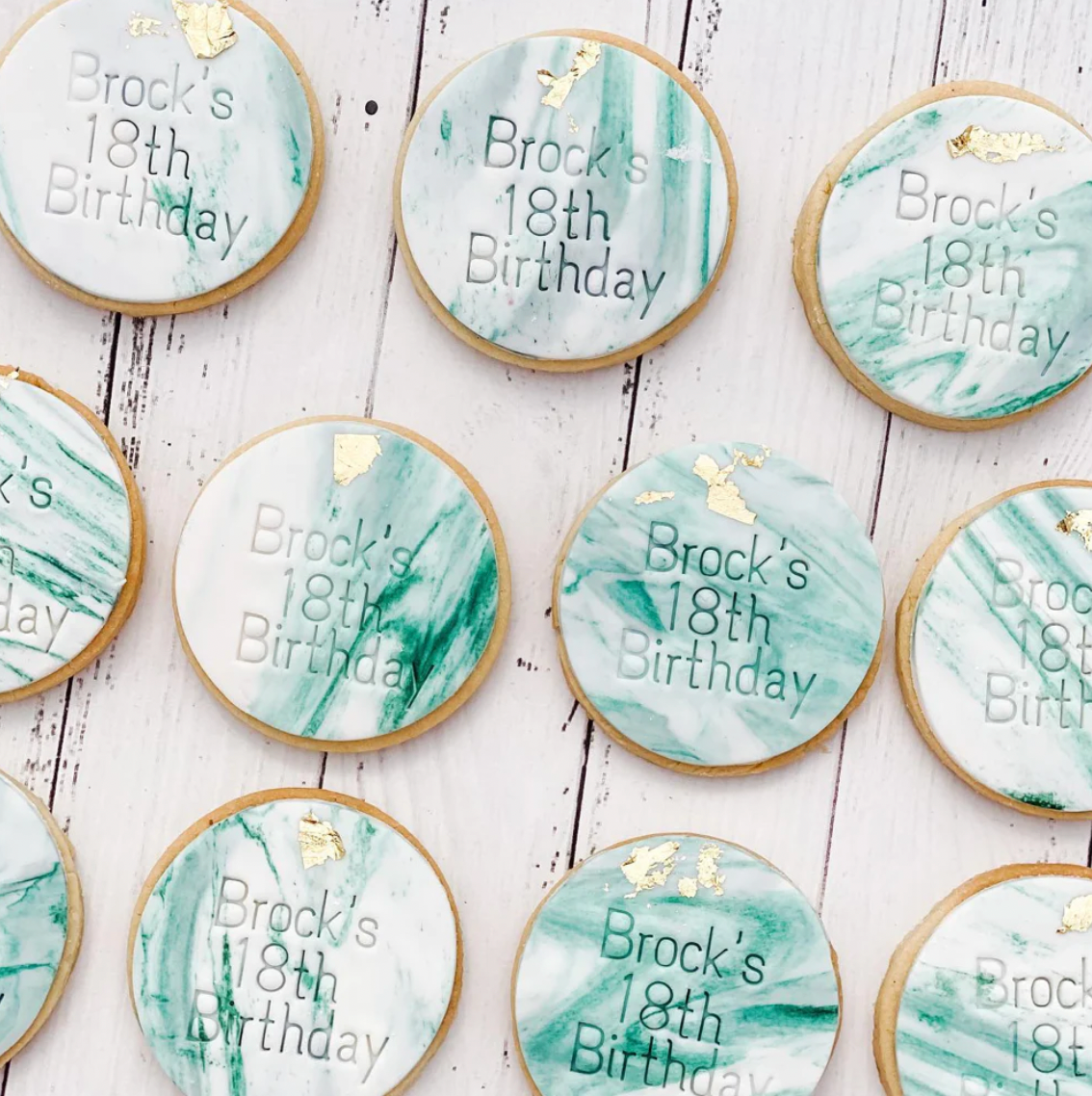green marble sugar cookies with bricks 18th birthday embossed into fondant icing and gold leaf. placed onto white background