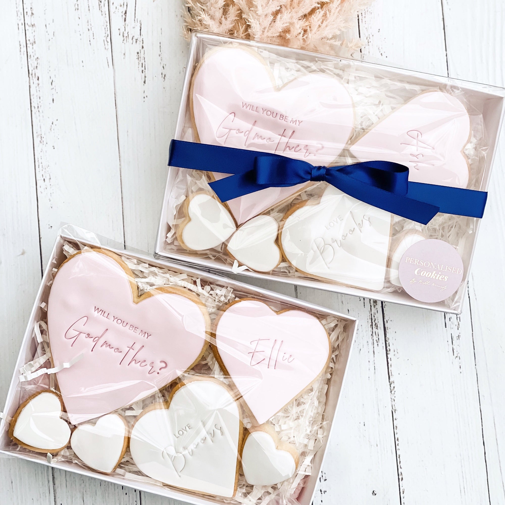 two boxes of 3 varied sized cookies presented in a white gift box and tied of with a navy ribbon. 