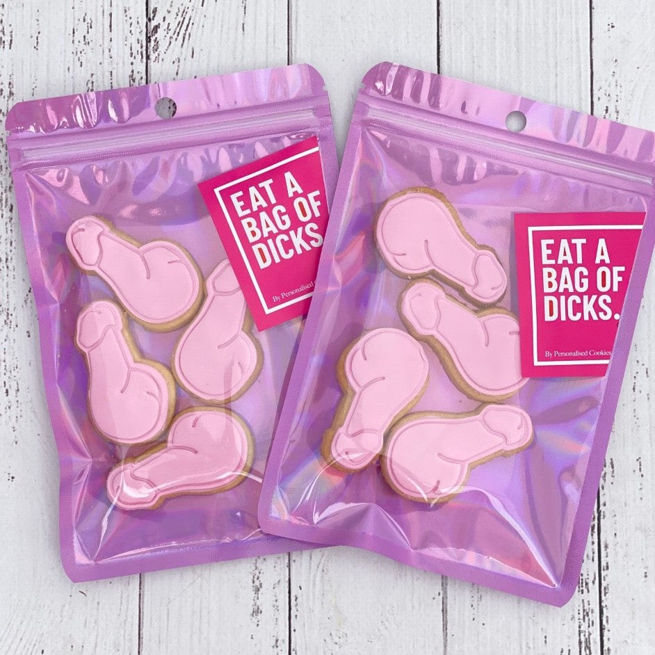 Four pink mini cookies shaped like penises, packaged in a pink metallic zip lock bag with a party-themed sticker on it.