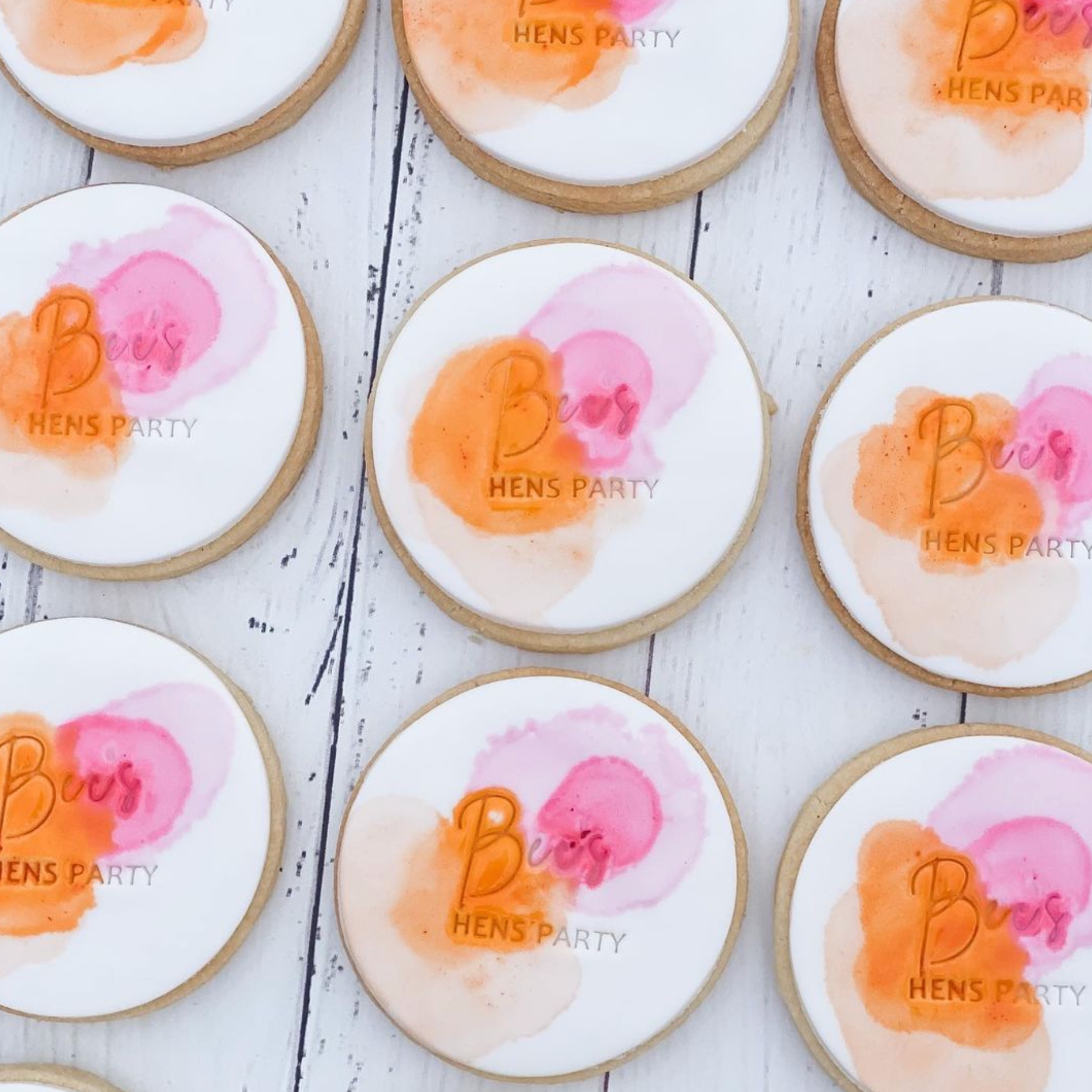 pink and orange watercolour cookies on a white wooden background